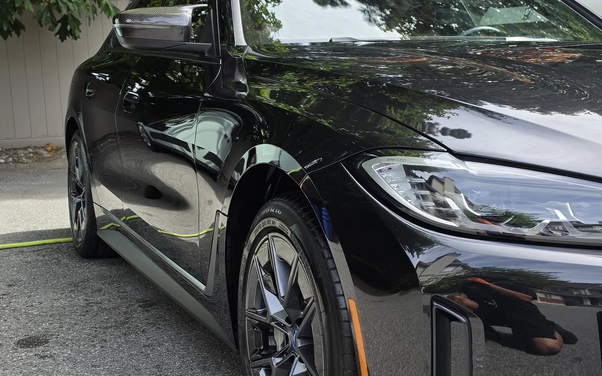 Deep gloss on the front quarter and wheel of a black BMW after paint correction in Surrey